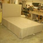 Custom build linen bed with upholstered headboard and removable skirt for underbed storage.